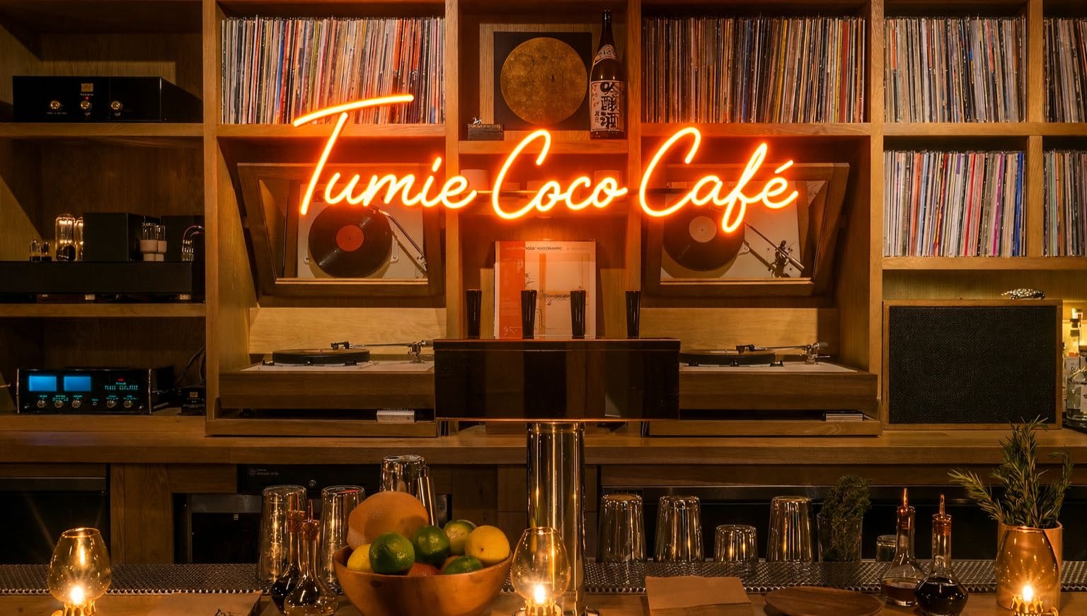 The Tumie Coco Café neon sign glowing over a wall of vinyl records